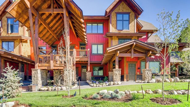 A multi-story building with a prominent wooden structure, stone pillars, and a well-maintained garden. - The Seasons at Keystone #1819 by Summit County Mountain Retreats (Keystone)