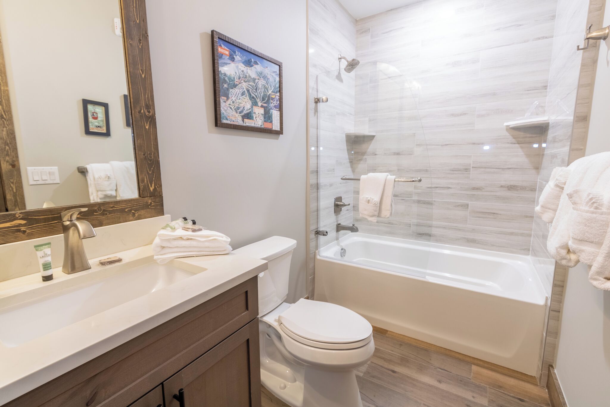 A modern bathroom with a large mirror, a sink, a toilet, and a glass-enclosed shower area.