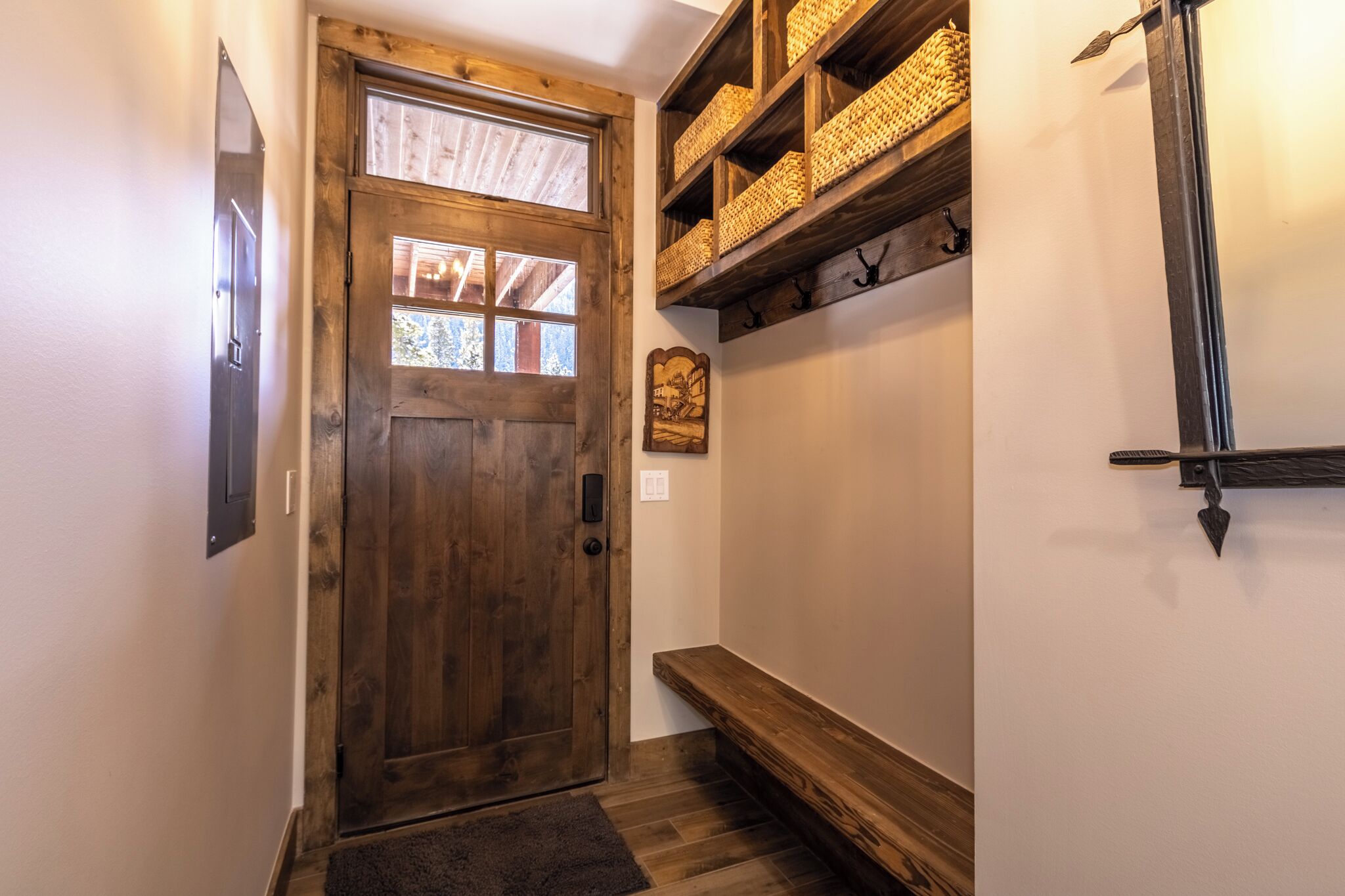 A wooden door with a window, a shelf with baskets, a coat rack, and a bench.