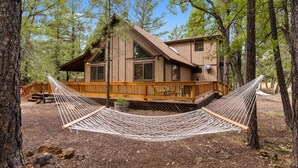 Une cabane dotée d’une terrasse en bois et d’un hamac.