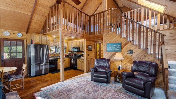 Un intérieur de chalet en bois spacieux, comprenant une cuisine, un coin repas et un escalier menant à un niveau supérieur.