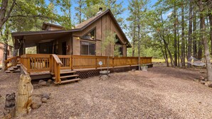 Une cabane dotée d’une terrasse en bois, d’un porche abrité et offrant une vue sur la forêt environnante.