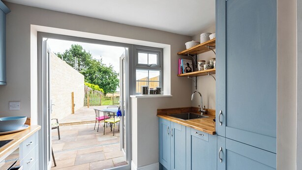 Een moderne keuken met blauwe kastjes, een houten aanrechtblad en een inbouwspoelbak.