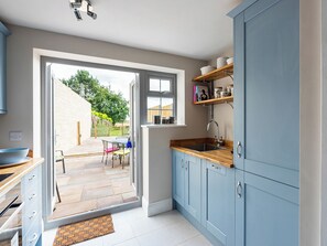 A modern kitchen with blue cabinets, a wooden countertop, and a built-in sink. - Charming cottage near lovely Stamford with cosy open fire and a rural location. (Stamford, near Easton-on-the-Hill)