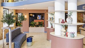 Un vestíbul modern amb taulell d'informació, zona de seients i plantes decoratives.