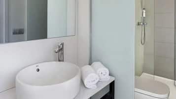 Un baño moderno con un lavamanos grande, un espejo y una ducha.