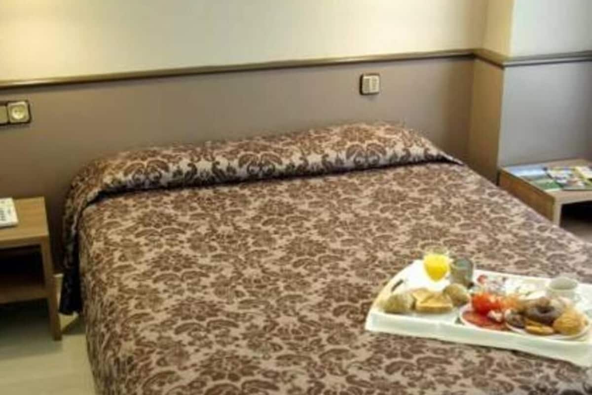 Une chambre d’hôtel avec un lit, une table de chevet et un plateau contenant des articles pour le petit-déjeuner.