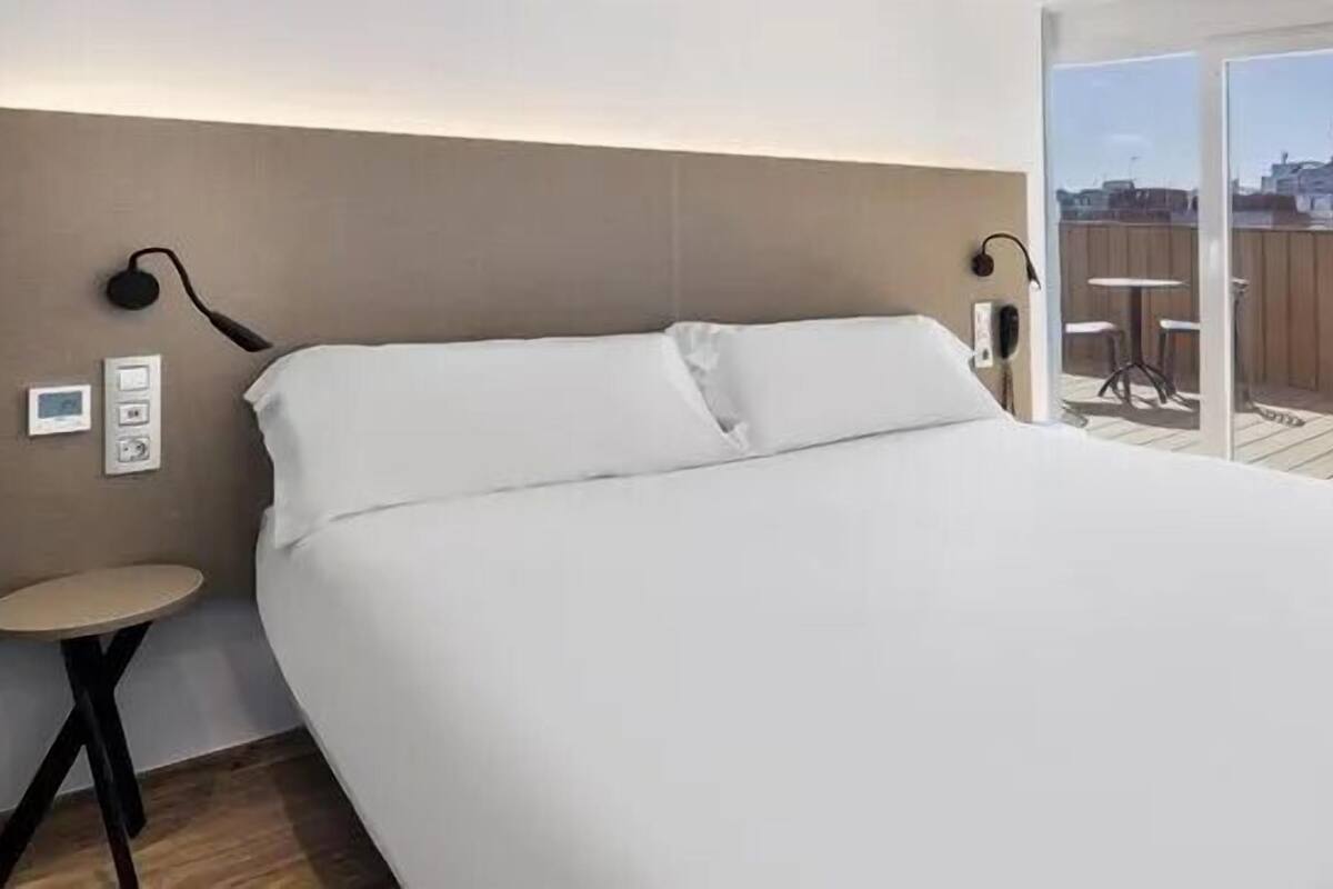 Une chambre d’hôtel moderne avec un grand lit, une petite table et un balcon offrant une vue agréable.