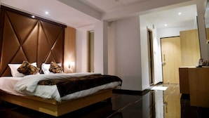 Una habitació d'hotel moderna amb un llit gran, un capçal de fusta, una taula de nit i un mirall.
