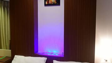 A hotel room with a bed, a nightstand, a wall-mounted painting, and a ceiling light.
