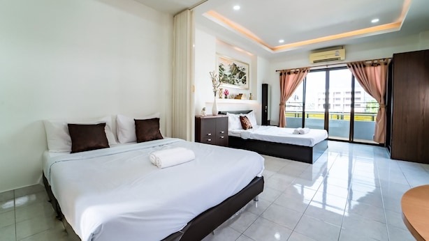 A hotel room with a large bed, a smaller bed, a vanity with a mirror, and a balcony with curtains. - OYO 75377 Check In House (Surat Thani)