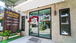 A building entrance with a glass door, a welcome mat, and a sign with contact information. - OYO 75377 Check In House (Surat Thani)