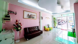 A modern lobby with a sofa, a flower vase, a framed picture, and a staircase. - OYO 75377 Check In House (Surat Thani)