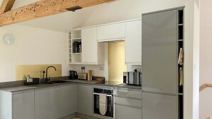 Une cuisine moderne avec des meubles gris, un four encastré et un four à micro-ondes.