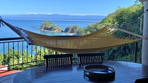 A hammock on a wooden deck with a view of the ocean and a distant mountain range. - New listing! Stunning views. Fifth floor apartment (Punta Leona)