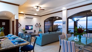A spacious living area with a glass dining table, blue sofa, and a balcony with a view. - New listing! Stunning views. Fifth floor apartment (Punta Leona)