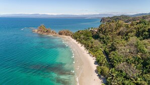 A coastal beach with clear turquoise waters, a sandy shore, and dense greenery. - New listing! Stunning views. Fifth floor apartment (Punta Leona)