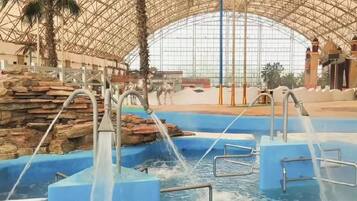 An indoor water park with multiple water slides and a large, arched glass ceiling.