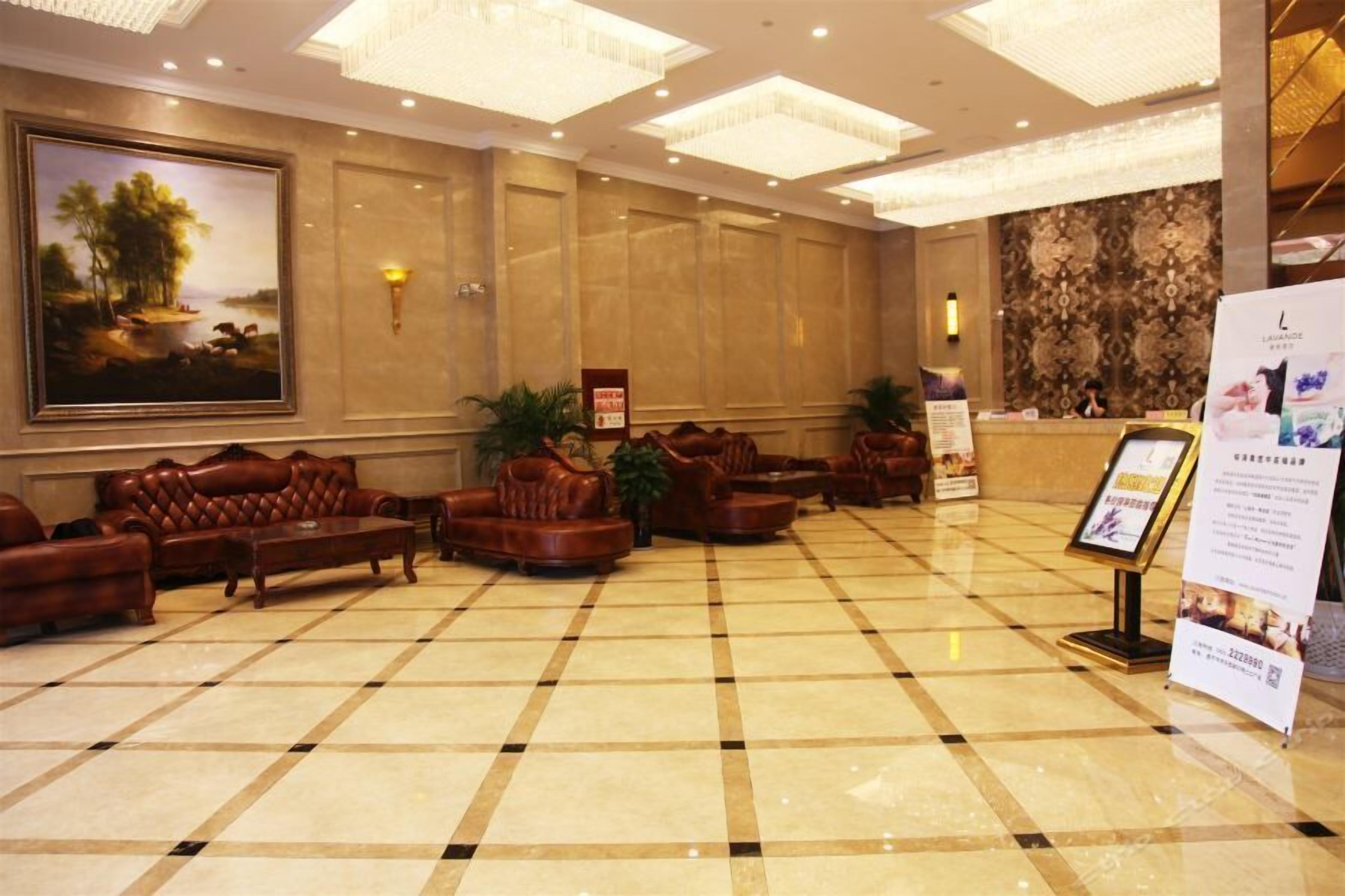 Eine Lobby mit Schachbrettmuster-Boden, Ledersofas, einem Empfangstresen und einem großen Gemälde an der Wand.