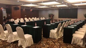 Un salón de conferencias con mesas, sillas y una pantalla para proyector.