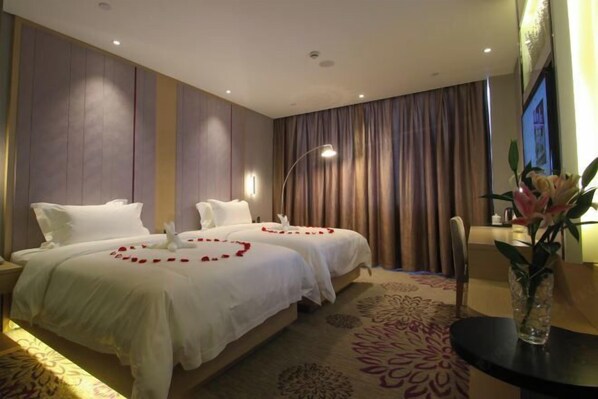 A hotel room with two beds, a large window with curtains, a vase with flowers, and a carpet with a floral pattern. - Lavande Hotel (Guangyuan Wanda Plaza Olympic Center) (Guangyuan)