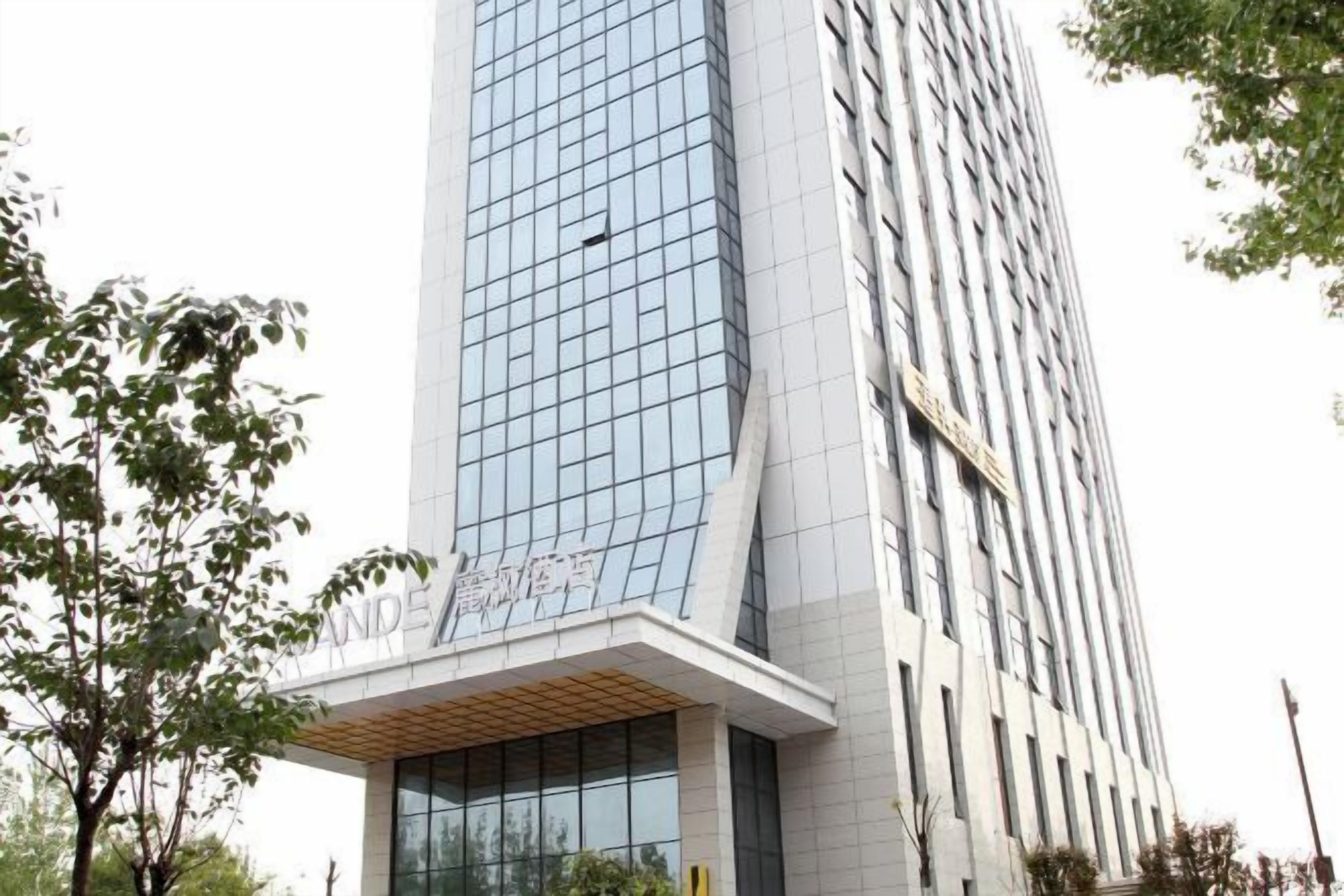 A modern building with a glass facade and a sign indicating it is a hotel.