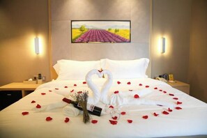 A hotel room with a bed, a bouquet of flowers, a bottle, and a heart-shaped towel arrangement. - Lavande Hotel (Guangyuan Wanda Plaza Olympic Center) (Guangyuan)