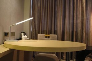 A modern room with a round table, a desk lamp, a chair, and a curtain backdrop. - Lavande Hotel (Guangyuan Wanda Plaza Olympic Center) (Guangyuan)