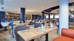 A modern restaurant with wooden tables, chairs, and a bar area. - Radisson Hotel Paris Le Bourget (Bonneuil-en-France)