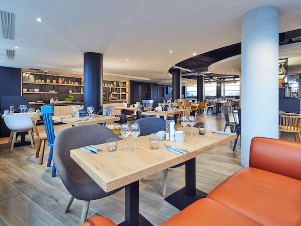 Un restaurant moderne avec des tables et des chaises en bois, ainsi qu’un espace bar.