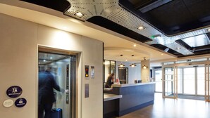 An elevator with a person inside, a reception desk, and a sign indicating 'ASCENSEUR' and 'SEMINAIRE'. - Radisson Hotel Paris Le Bourget (Bonneuil-en-France)
