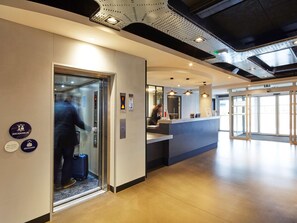 An elevator with a person inside, a reception desk, and a sign indicating 'ASCENSEUR' and 'SEMINAIRE'. - Radisson Hotel Paris Le Bourget (Bonneuil-en-France)