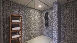 A shower with mosaic tile walls, a wooden shelf with towels, and a glass partition. - Radisson Hotel Paris Le Bourget (Bonneuil-en-France)