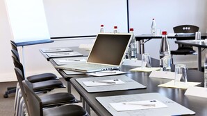 A conference room with a laptop on a table, water bottles, and name cards. - Radisson Hotel Paris Le Bourget (Bonneuil-en-France)