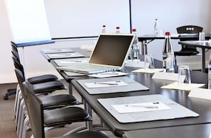 Une salle de conférence avec un ordinateur portable sur une table, des bouteilles d’eau et des cartes nominatives.
