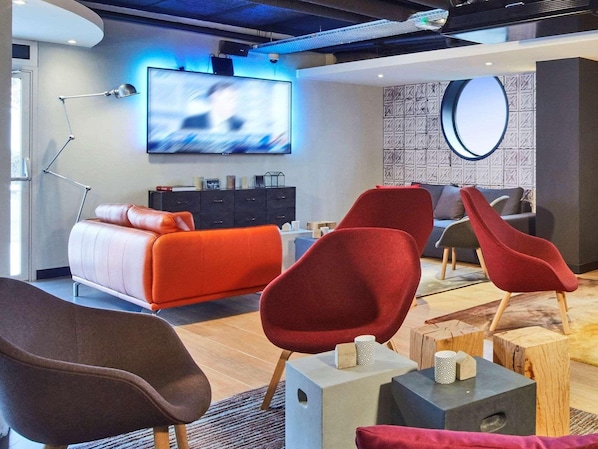 Ein modernes Wohnzimmer mit einer Couch, roten Sesseln, einem Fernseher und einer Wandverkleidung.