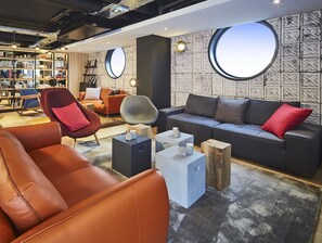 A modern living room with leather sofas, a coffee table, and a bookshelf. - Radisson Hotel Paris Le Bourget (Bonneuil-en-France)