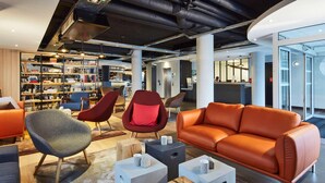 A modern lounge area with seating, a bookshelf, and a reception desk.
