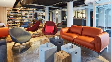 Un espace détente moderne comprenant des sièges, une bibliothèque et un comptoir d’accueil.
