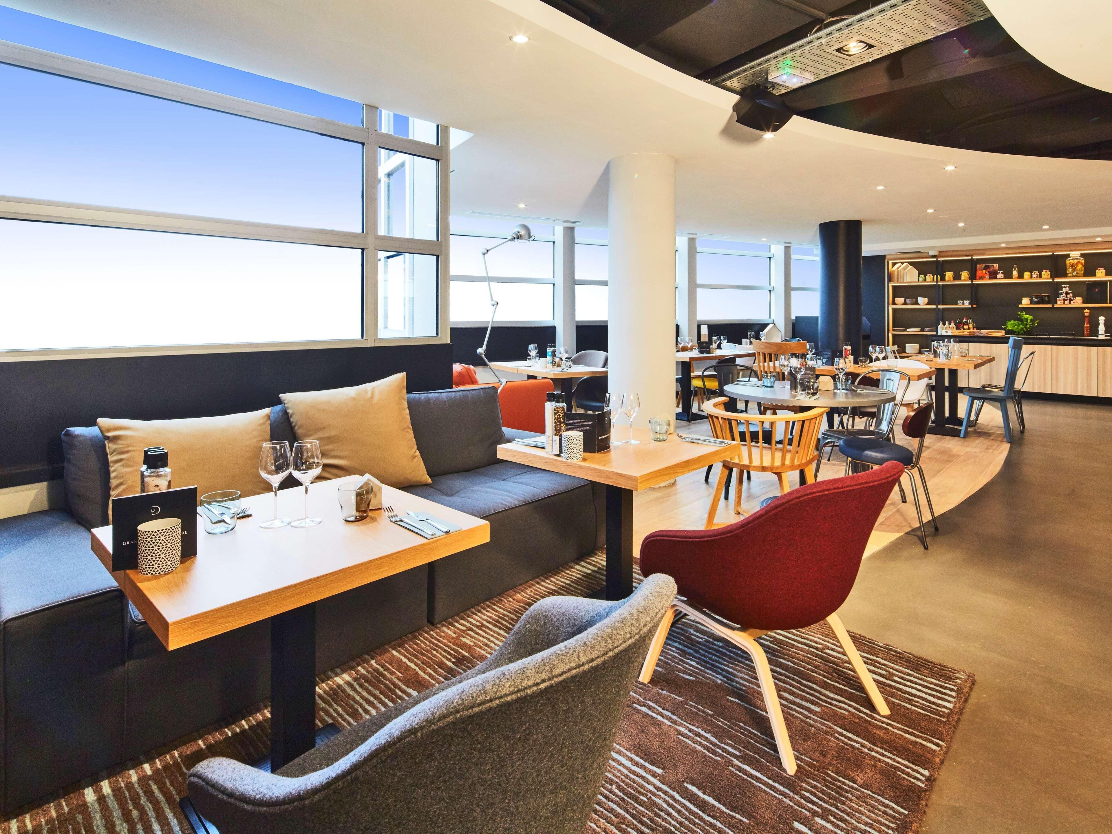 Un restaurant moderne doté d’un espace pour s’asseoir, de tables et d’un bar.