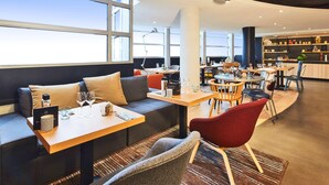 A modern restaurant with seating, tables, and a bar area. - Radisson Hotel Paris Le Bourget (Bonneuil-en-France)
