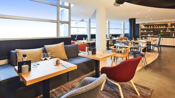 Un restaurant moderne doté d’un espace pour s’asseoir, de tables et d’un bar.