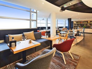 A modern restaurant with seating, tables, and a bar area. - Radisson Hotel Paris Le Bourget (Bonneuil-en-France)