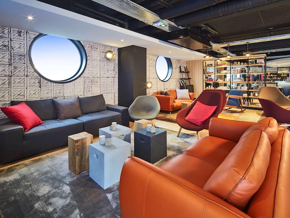 Un espace de détente moderne comprenant un canapé, des fauteuils, une table basse et une bibliothèque.