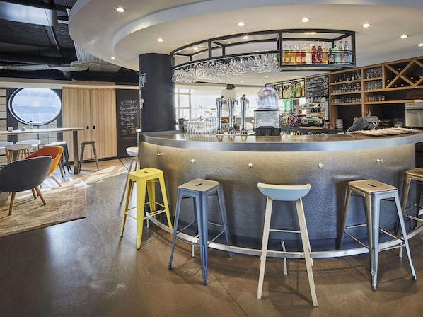 Un espace bar moderne, doté de tabourets, d’un comptoir et d’une variété de verres et de bouteilles.