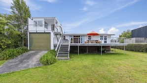 A modern two-story house with a covered patio, a staircase, and a garage.