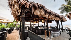 A beachside bar area with thatched umbrellas, wicker furniture, and a wooden deck. - Club Wyndham Denarau Island, Trademark Collection by Wyndham (Nadi)