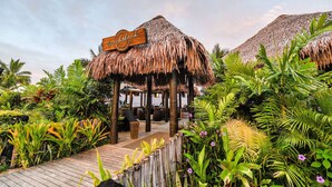 A beachside resort with thatched-roof structures, lush tropical plants, and a wooden walkway. - Club Wyndham Denarau Island, Trademark Collection by Wyndham (Nadi)