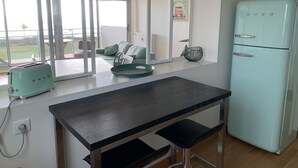 Une cuisine avec un réfrigérateur de couleur turquoise, un grille-pain et une fenêtre donnant sur une terrasse.
