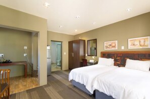 A hotel room with a large bed, a desk, a chair, a wardrobe, and a bathroom visible through an open door. - Africlassic Rivonia by BON Hotels (Sandton)